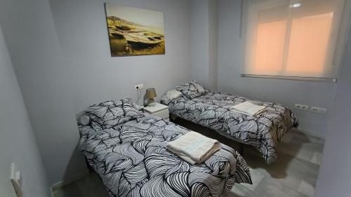 福恩吉罗拉Apartamentos La Casa de Bebita的两张睡床彼此相邻,位于一个房间里