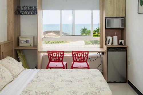 卡塔赫纳Apartamento Ganem 505a的卧室配有两张红色椅子,设有一张床和一个窗户