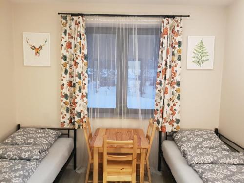 科曼恰Przystanek Letnisko的客房设有两张床、一张桌子和一扇窗户。