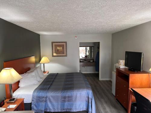 威克斯巴勒Wilkes-Barre Inn & Suites的配有一张床和一台平面电视的酒店客房