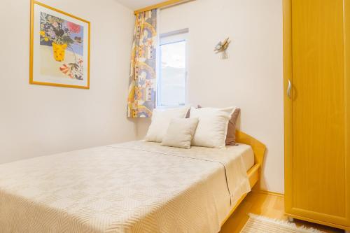 奥米沙利Apartman 3的一间卧室配有一张带白色床单的床和一扇窗户。