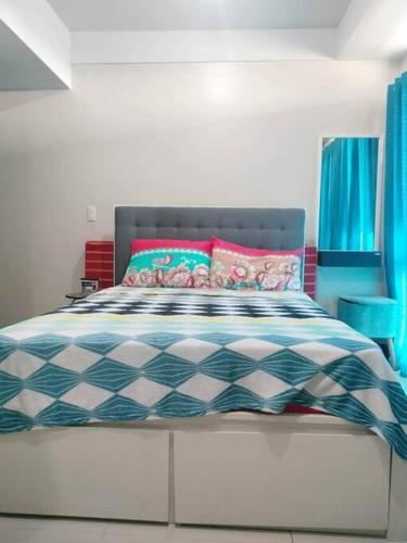 马尼拉Cubao Manhattanheights U31N TB, Studio Unit的一间卧室配有一张带蓝色和粉红色枕头的床