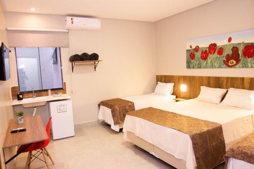 戈亚尼亚Fiori Suítes的酒店客房配有两张床和一张书桌