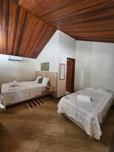 南蒙蒂阿莱格里Pousada Sítio do Sossego的一间卧室设有两张床和木制天花板