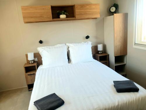 鲁西隆地区卡内MH Luxury Eden Mar Estang Plage 100m 2TV 2 Sdb Baby confort Plus的卧室配有白色床和2条黑色毛巾