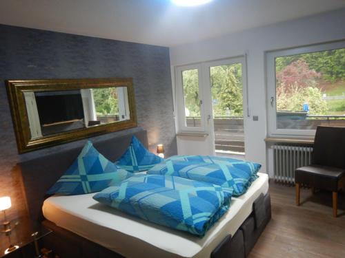 魏申费尔德Pension Pulvermühle的一间卧室配有一张带蓝色枕头和镜子的床