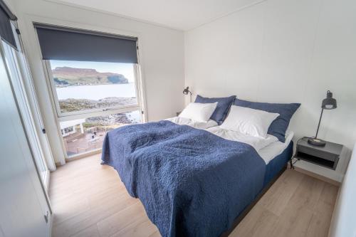 RundeRunde Panorama - Trollvogga的一间卧室配有一张带蓝色毯子的床和窗户。