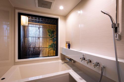 京都Rinn Kyoto Station的带淋浴和浴缸的浴室以及窗户。