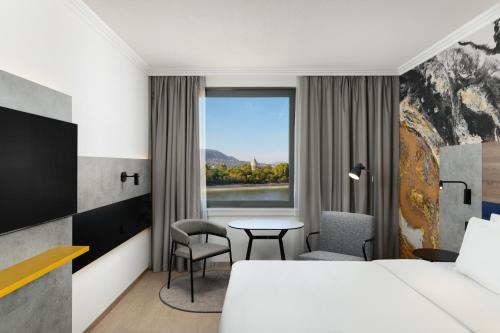 布达佩斯贺莉亚丹乌比斯酒店的酒店客房设有床、桌子和窗户。