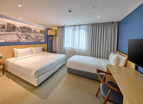 首尔Travelodge Myeongdong City Hall的酒店客房配有两张床和一张书桌