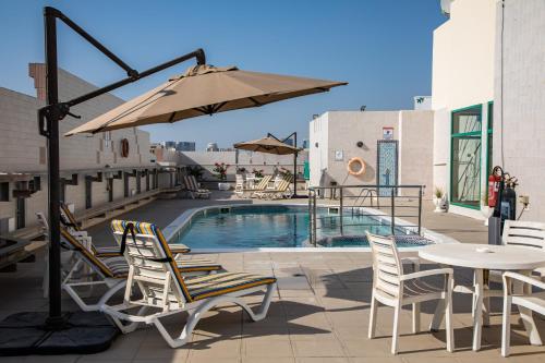 迪拜West Zone Pearl Hotel Apartment的一个带椅子和遮阳伞的庭院和一个游泳池
