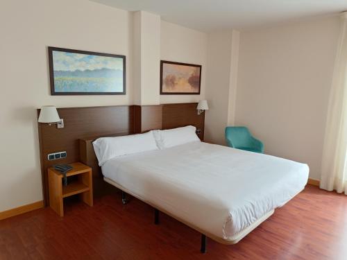 帕伦西亚国会宫酒店的卧室配有白色的床和蓝色椅子