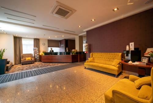 奥尔什丁沃明斯基酒店及会议中心的大堂设有黄色的沙发和等候室