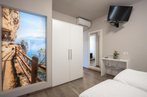 加尔达湖滨洛丽酒店的卧室设有推拉门,墙上挂有绘画作品