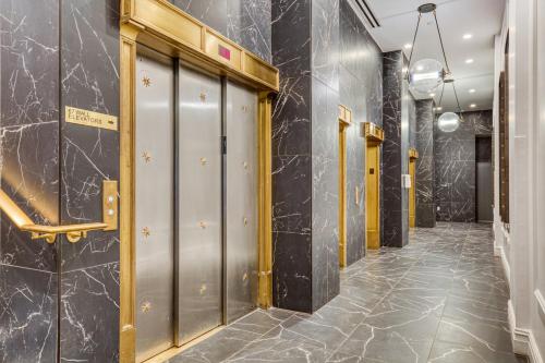 纽约FiDi 1BR w luxury Gym Doorman Rooftop NYC-13的走廊上设有金属门和大理石墙壁