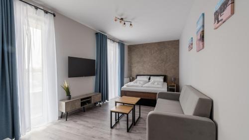 科沃布热格Horyzont Apartamenty -Bałtycka2 - SAUNA & FITNESS - ŚNIADANIA的一间卧室配有一张床、一张沙发和一台电视。