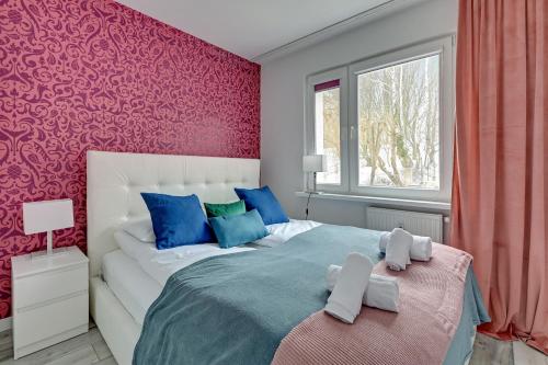 格丁尼亚Comfort Apartments Falista的一间卧室配有一张带粉红色墙壁的大床