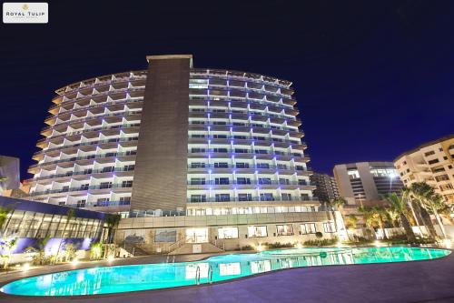 丹吉尔市中心皇家金色郁金香酒店的一座大型建筑,前面设有一个游泳池