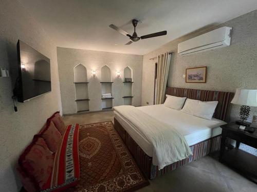 尼兹瓦Date Palm Inn的一间卧室配有一张床、一把椅子和电视
