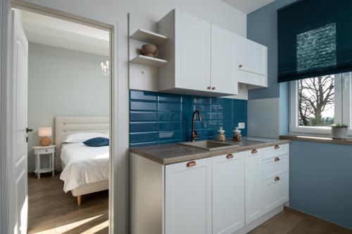 泽敏Apartments Pausa的厨房配有白色橱柜、蓝色的墙壁和一张床