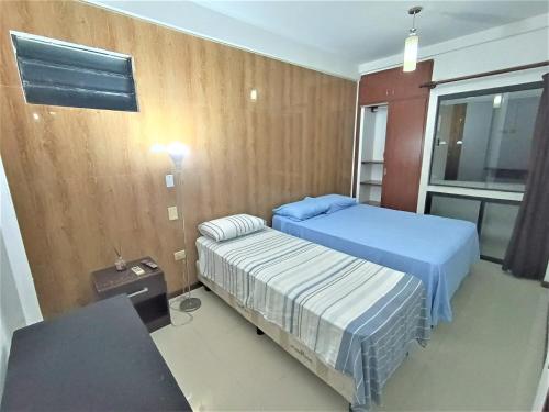 圣克鲁斯Departamentos en Edificio Acrebol Santa Cruz的一间卧室设有两张床、一张桌子和一个窗口