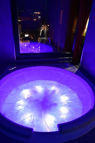 斯科普里Smart Luxury Penthouse Suites - Private Sauna, Hot-Tub, Home Cinema at the best Location in Skopje的客房内带灯的大型紫色浴缸