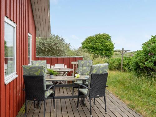 约灵Holiday Home Stella - 700m from the sea in NW Jutland by Interhome的红色房子上带桌椅的木甲板