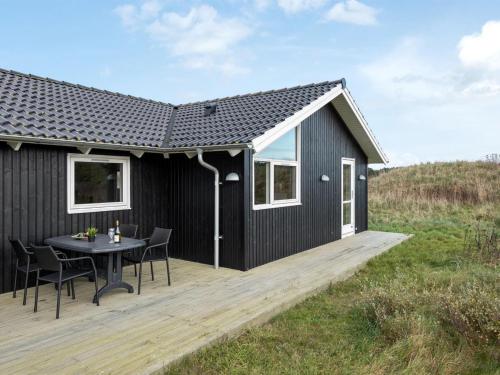 希茨海尔斯Holiday Home Frejdis - 1-1km from the sea in NW Jutland by Interhome的木制甲板上一张桌子的黑色房子