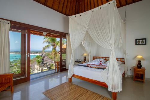蓝梦岛勒姆博南悬崖别墅的一间卧室设有一张天蓬床,享有海景