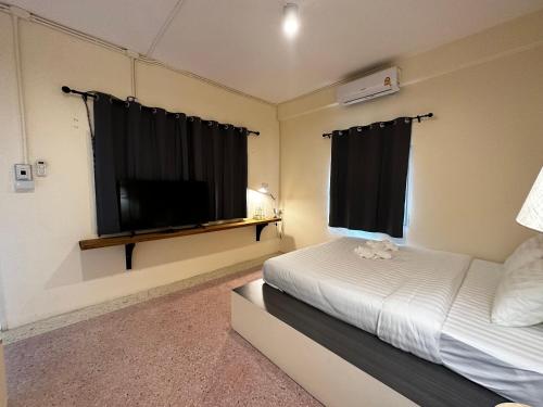 洛坤府Norm Space Hostel NST的一间卧室配有一张床和一台平面电视