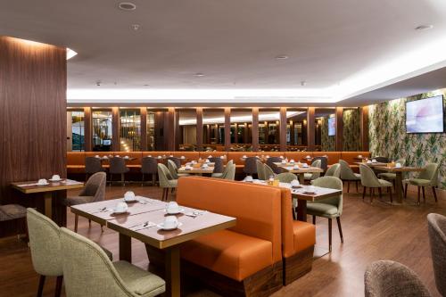 波尔图TURIM Oporto Hotel的一间带桌椅和电视的餐厅