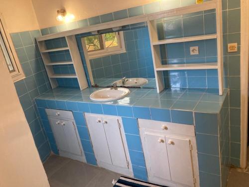 NdanganeVilla avec piscine à Ndangane的蓝色瓷砖浴室设有水槽和镜子