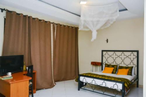 坎帕拉Naalya Motel的一间卧室配有一张床、一张书桌和一台电视
