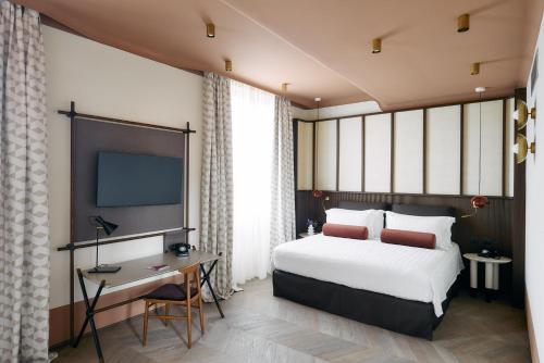 罗马Palazzo Velabro, a Member of Design Hotels的一间卧室配有一张床、一张书桌和一台电视。