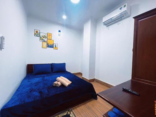 芹苴Nhan Tay Hostel的一间卧室配有一张蓝色的床和一张桌子