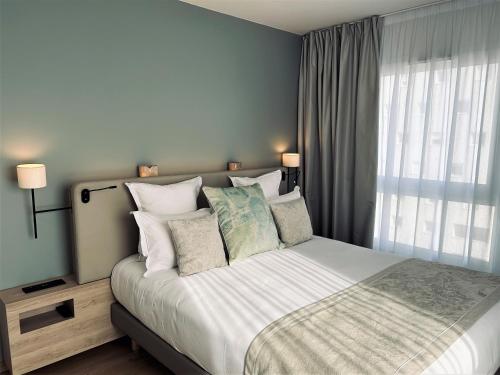塞纳河畔伊夫里Residhome Quai d’Ivry的卧室配有带枕头的大床和窗户。