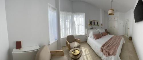 韦尔瓦Hoyo 20 de La Monacilla Golf的白色卧室配有床和椅子