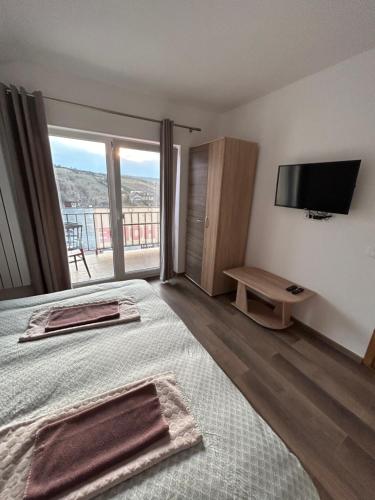DezmirGiulia Home的一间卧室设有一张床、一台电视和一个阳台。