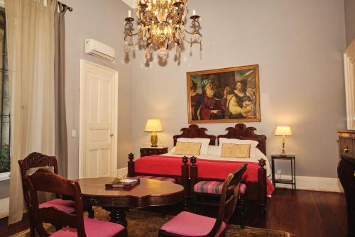 乌拉圭河畔康塞普西翁Palacio Santa Candida的一间卧室配有一张床、一张桌子和一个吊灯。