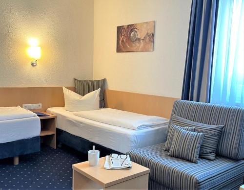 金茨堡Hotel Bettina garni的酒店客房,设有两张床和一张沙发