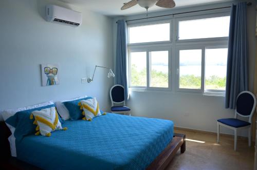 博卡奇卡Casa Tanamera的一间卧室配有蓝色的床、两把椅子和窗户