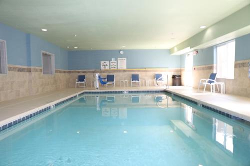 阿尔伯克基阿尔伯克基机场智选假日套房酒店 的一个带蓝色椅子的大型游泳池