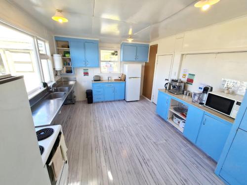 TuatapereRarakau Lodge的厨房铺有木地板,配有蓝色橱柜。