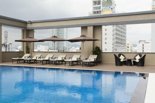 格卢市社孟青格兰德库阿尔酒店的一座大楼内的游泳池,配有椅子和遮阳伞