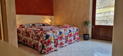 Castel FocognanoCasa Carda di Lai Loretta的一间卧室配有一张带鲜花毯子的床和窗户。