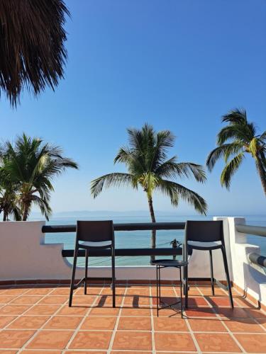 布塞里亚斯Villa Cobojo的棕榈树阳台的两把椅子和一张桌子
