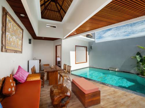 金巴兰Avery Le Nixsun Villas Uluwatu by Waringin Hospitality的客厅设有游泳池、桌子和沙发