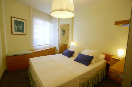 坎布里尔斯Apartamentos Alquihouse Vilafortuny的一间卧室配有一张带两个蓝色枕头的床