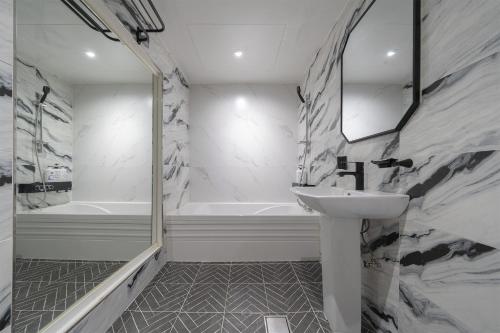 IksanBYTHS CURVE HOTEL JEONGBUK IKUSAN的浴室配有盥洗盆和浴缸。