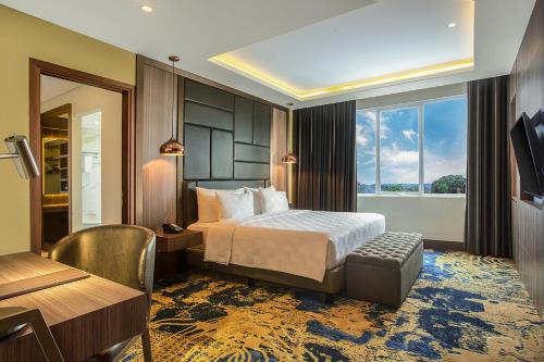 FandoiSwiss-Belhotel Cendrawasih, Biak的配有一张床、一张书桌和一扇窗户的酒店客房